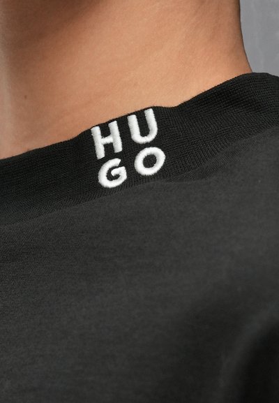 Черна тениска с рипсена яка; има бяло бродирано лого "HUGO" на деколтето; гладка текстура, неформален дизайн.