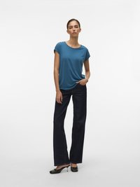 Tricou albastru cu mânecă scurtă, asortat cu pantaloni evazați din denim închis și pantofi cu toc negri. Material neted, cu o croială lejeră.