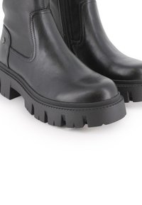 Botas de cuero negro hasta el tobillo con una suela de goma gruesa y texturizada. Presenta un cierre lateral y un diseño minimalista. Acabado suave con punta redondeada.