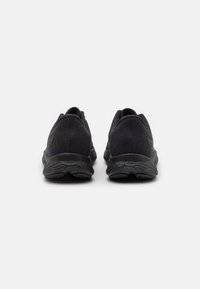Zapatillas deportivas negras con parte superior texturizada y talón reforzado. Presenta una suela acolchada con un patrón ondulado para mayor soporte.
