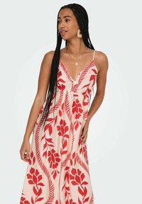 Robe maxi en tissu léger avec un motif floral rouge. Bretelles spaghetti et corsage ajusté avec une jupe évasée. Texture lisse.