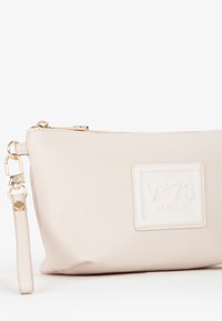 Beige leren tas met een textuur oppervlak, voorzien van een opvallende geperste logo patch en een gouden rits met een afneembare riem.