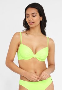 Neon grünes Bikini-Set mit einem geknoteten Frontdetail. Das Oberteil hat verstellbare dünne Träger und eine glatte, dehnbare Textur.