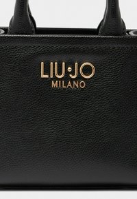Sac en cuir noir à texture granuleuse avec deux poignées supérieures et le logo doré "LIU·JO MILANO" affiché en évidence à l'avant.