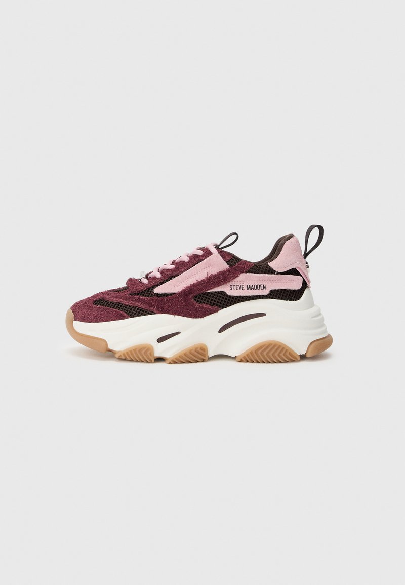 Zapatilla deportiva de malla y ante color burdeos con detalles en rosa, suela media blanca gruesa y suela exterior de goma marrón. Cuenta con tira para tirar y cordones.