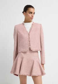Rood en wit tweed jasje met rafelige randen, cropped ontwerp, gecombineerd met een flare rok met bijpassende rafelige accenten.