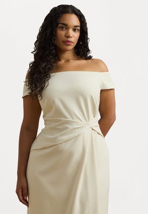 Beige off-the-shoulder mekko, jossa on kierretty etuosa, valmistettu pehmeästä kankaasta, jossa on sileä pinta ja virtaava siluetti.