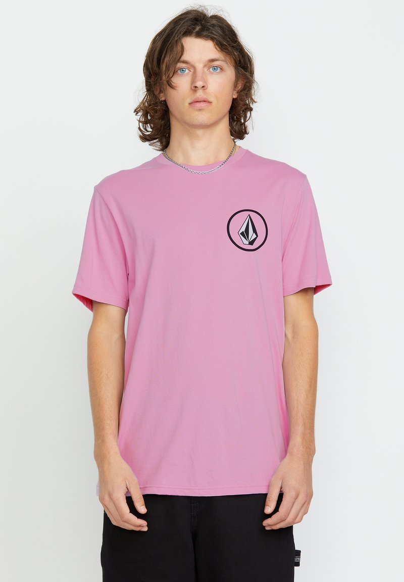 Light pink short-sleeve t-shirt with a round black logo on the left chest. Soft fabric and a relaxed fit. No patterns or accents visible.