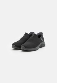 Fekete slip-on cipők texturált hálós felsőrésszel, puha béléssel és tartós gumitalppal. Rugalmas designnal és minimalista kiegészítőkkel rendelkezik.