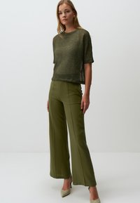 Haut à manches courtes en tricot lâche de couleur vert olive, associé à un pantalon large taille haute en vert olive. Tissu texturé et structure subtile.