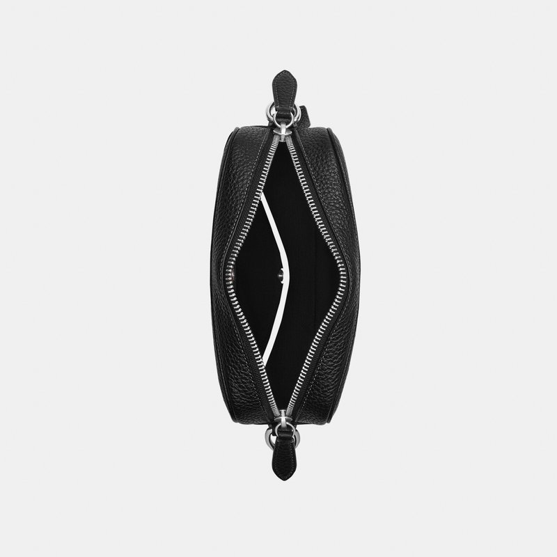 Bolso bandolera de cuero negro texturizado con cremallera plateada parcialmente abierta, mostrando un bolsillo interior minimalista sobre un fondo blanco liso.