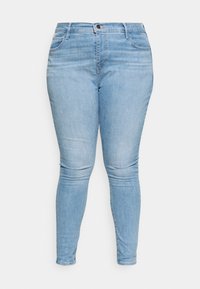 Lysblå denim skinny jeans med medium høj talje, der har forlommer, lynlås og subtile falmninger langs benene.