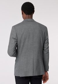 Grau karierter Blazer mit einem unkomplizierten Schlitz, Schalkragen und Knopfmanschetten. Hergestellt aus strukturiertem Stoff, mit taillierter Passform und minimalistischem Design.