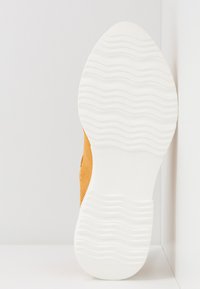 Orange mesh sneaker with a textured white rubber sole, featuring a subtle wave pattern and size indicator embossed on the side.