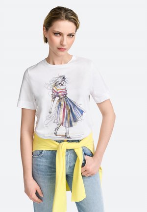White cotton t-shirt featuring a colorful illustration of a woman in a striped dress. Paired with light denim jeans and a yellow sweater tied at the waist.