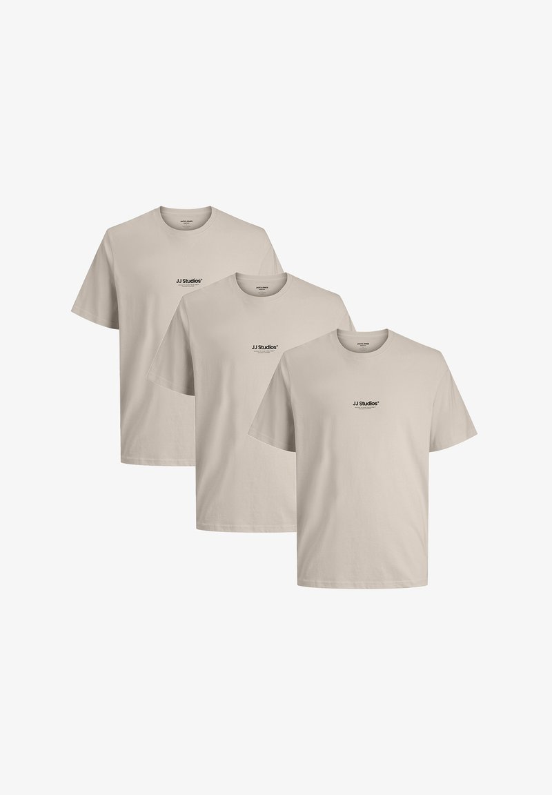 Drie t-shirts met korte mouwen in een lichte beige kleur. Het materiaal lijkt zacht en heeft een klein zwart logo op de borst.