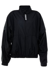 Chaqueta cortavientos negra con un cuello alto, cremallera frontal, puños elásticos y dobladillo; presenta una textura sutil y la marca "Reebok" en el tirador de la cremallera.