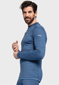 Blaues langärmliges Sportoberteil aus Mischgewebe, mit Rundhalsausschnitt, flachen Nähten und Logodetail am linken Ärmel.