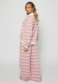 Randig lounge-set i rosa, vitt och lavendel; inkluderar en lös sittande långärmad topp och byxor med vida ben och ribbade muddar.