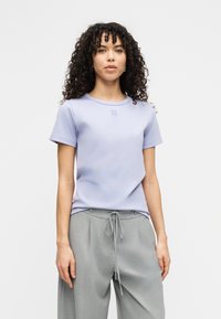 Ανοιχτό μωβ κοντομάνικο T-shirt με στρογγυλή λαιμόκοψη και κεντημένο λογότυπο. Συνδυασμένο με γκρι παντελόνια με κορδόνι για άνετη εφαρμογή.