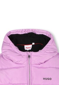 Opgestikte pufferjack in lichtroze met een zwart fleece interieur, voorzien van een voorkant met rits, kap en het HUGO-logo op de borst.