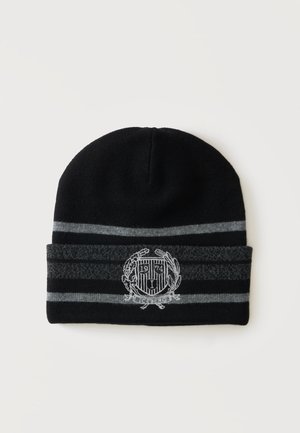 Bonnet en tricot noir avec des rayures horizontales grises et un blason brodé blanc montrant "1974" et du texte sous le blason.