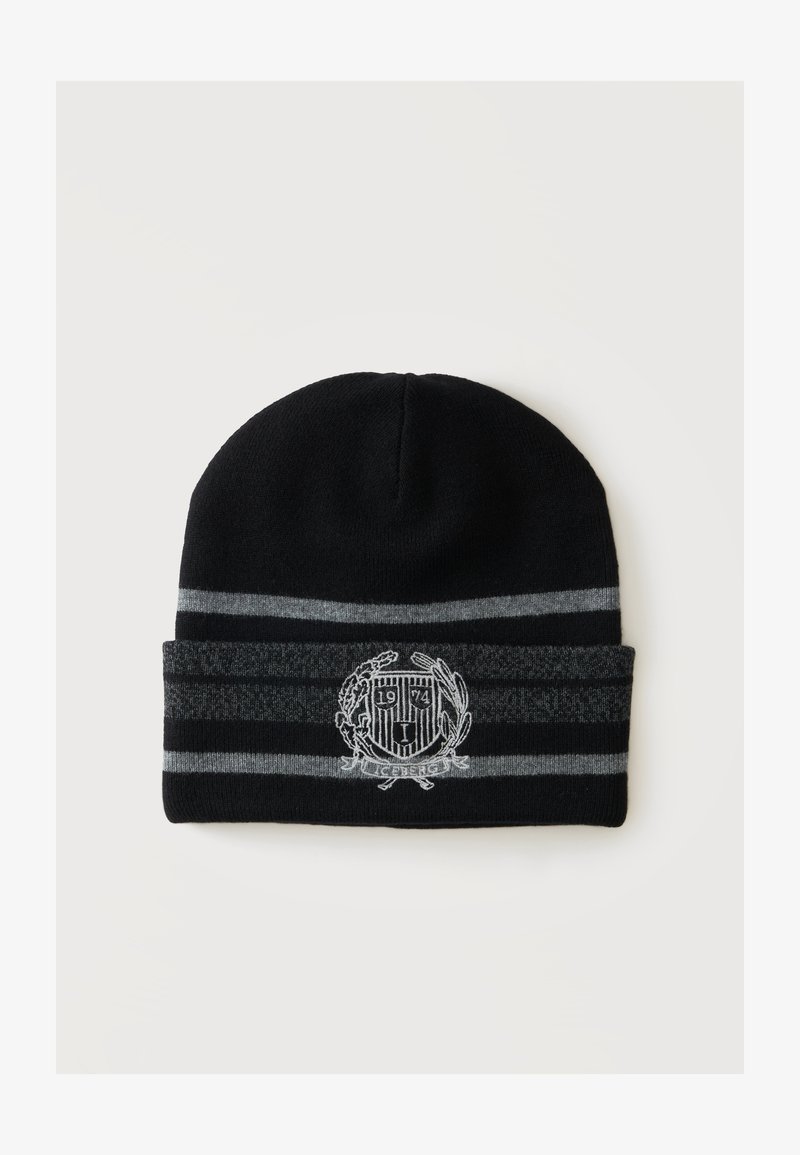 Bonnet en tricot noir avec des rayures horizontales grises et un blason brodé blanc montrant "1974" et du texte sous le blason.