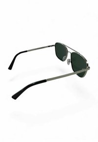 Metalowe okulary przeciwsłoneczne w stylu lotniczym z zielonymi soczewkami, srebrną oprawką i czarnymi końcówkami zauszników. Posiadają noski oraz cienką, lekką konstrukcję.