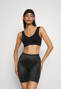 Brassière de sport noire avec encolure dégagée et larges bretelles, associée à un short de compression noir brillant taille haute. Texture lisse, coupe ajustée.