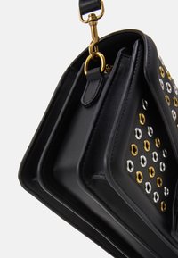 Borsa in pelle nera con borchie metalliche in oro e argento. Presenta un design strutturato con una tracolla e una chiusura con zip.
