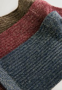 Trzy skarpetki w prążki w kolorach ciemno-brązowym, burgundowym i granatowym, każda z metalicznymi nitkami, prezentujące miękką teksturę i różne odcienie.