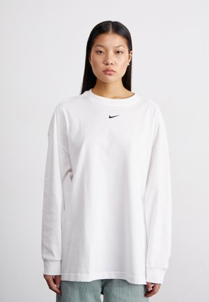 Biela dlhá rukávová tričko z mäkkej bavlny s okrúhlym výstrihom a spustenými ramenami; obsahuje malé čierne logo Nike na hrudi.