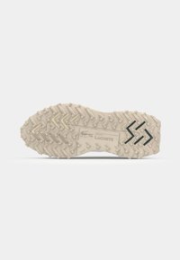 Zool van een sneaker in lichtbeige met een gestructureerde rubberen grip, met een zigzagpatroon en een reliëflogo voor grip en designdetail.