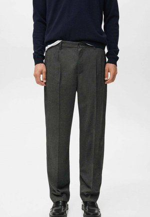 Pantalones de lana gris carbón con un diseño de pierna recta, que presentan pliegues, bolsillos laterales y una cinturilla tradicional. Llevados con un suéter azul marino.