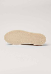 Suela de zapato de color crema, con un patrón de espiga para tracción. Textura suave sin logotipos visibles ni detalles adicionales.