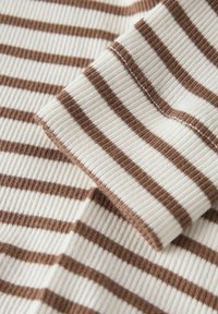 Bavlnená tkanina v smotanovej farbe s hnedými horizontálnymi pruhmi, s rebrovanou textúrou. Okraje majú čisté prešitie a jemný povrch.