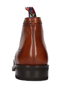 Talons de chaussure habillée en cuir marron avec une semelle noire et une languette en tissu coloré, présentés sur un fond blanc.