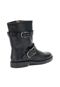 Botín de cuero negro hasta el tobillo con dos correas ajustables de hebilla metálica, puntera redonda y tacón bajo. Acabado texturizado con detalles de costura.