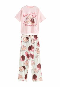 Lyserød bomulds t-shirt med en grafik der har tekst, parret med hvide pyjamasbukser prydet med dessertmønstre i pink og brun.