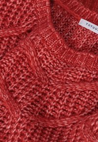 Czerwony sweter dzianinowy z teksturowanym wzorem i splecionymi wzorami, szerokim dekoltem oraz widoczną metką na kołnierzu.