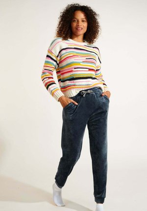 Bunter gestreifter Pullover mit einem gerippten Rundhalsausschnitt, kombiniert mit marineblauen Velours-Jogginghosen mit Seitentaschen und einem Kordelzugbund.