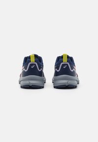 Zapatos deportivos con parte superior en azul marino, acentos en rosa y suela gris. Presenta un lengüeta trasera amarilla y material texturizado para mayor agarre.