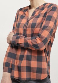 Långärmad, knappad skjorta i orange och mörkblått rutmönster, med avslappnad passform, kraglös halsringning och knappärmar.