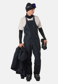 Salopette de ski noire en tissu résistant, avec des bretelles ajustables, plusieurs poches et un design élégant. Les accessoires comprennent des gants et une veste.