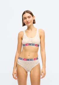 Δαντελωτό bralette και αντίστοιχες εσώρουχες σε κρέμα με μαύρη και κόκκινη ζώνη "DIESEL". Στρογγυλή λαιμόκοψη, επίπεδες ραφές και λεπτομέρειες φλοράλ μοτίβου.
