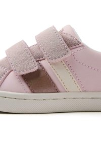 Zapatillas rosas con una parte superior de cuero suave y detalles en ante, dos correas de velcro y una suela de goma blanca. Variaciones sutiles de color presentes.