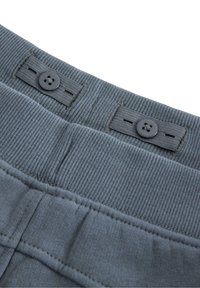 Grijze katoenen tailleband met ribbelstructuur, voorzien van twee zwarte knopen en vlakke stikseldetails. Het ontwerp is eenvoudig en functioneel.