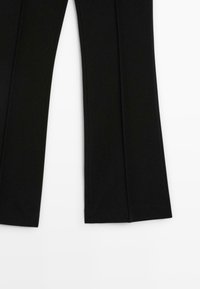 Pantaloni neri su misura con gambe larghe a campana, mostrati in piatto su uno sfondo bianco.