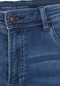 Denim-Jeans in dunkelblauer Farbe, mit kontrastierenden Nähten, einem metallischen Knopfverschluss und einem CASAMODA-Logo am Bund.