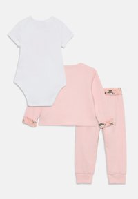 Dvodelni dječji outfit koji se sastoji od bijele body majice s kratkim rukavima i ružičaste majice s dugim rukavima s cvjetnim uzorcima na manžetama, te odgovarajućih ružičastih hlača.